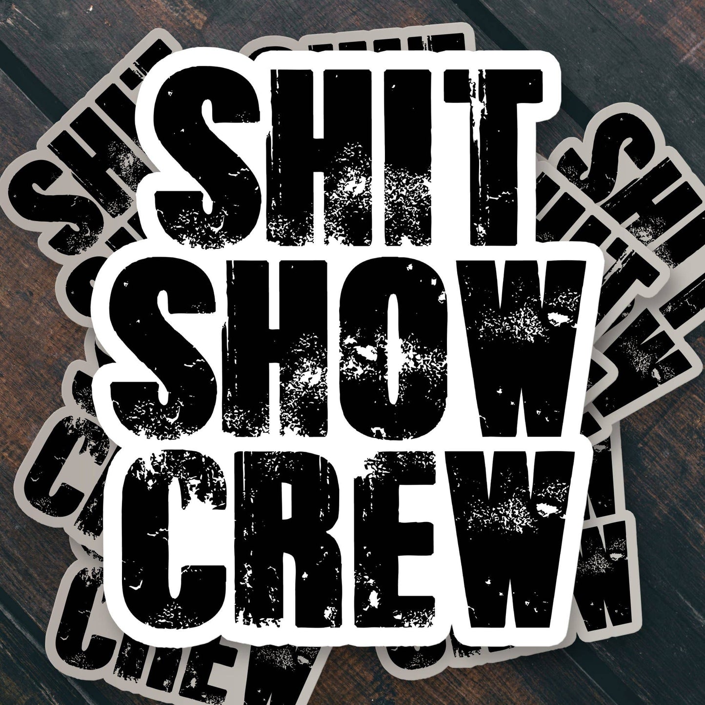 Stacked SHIT SHOW CREW stickers on dark wood background.