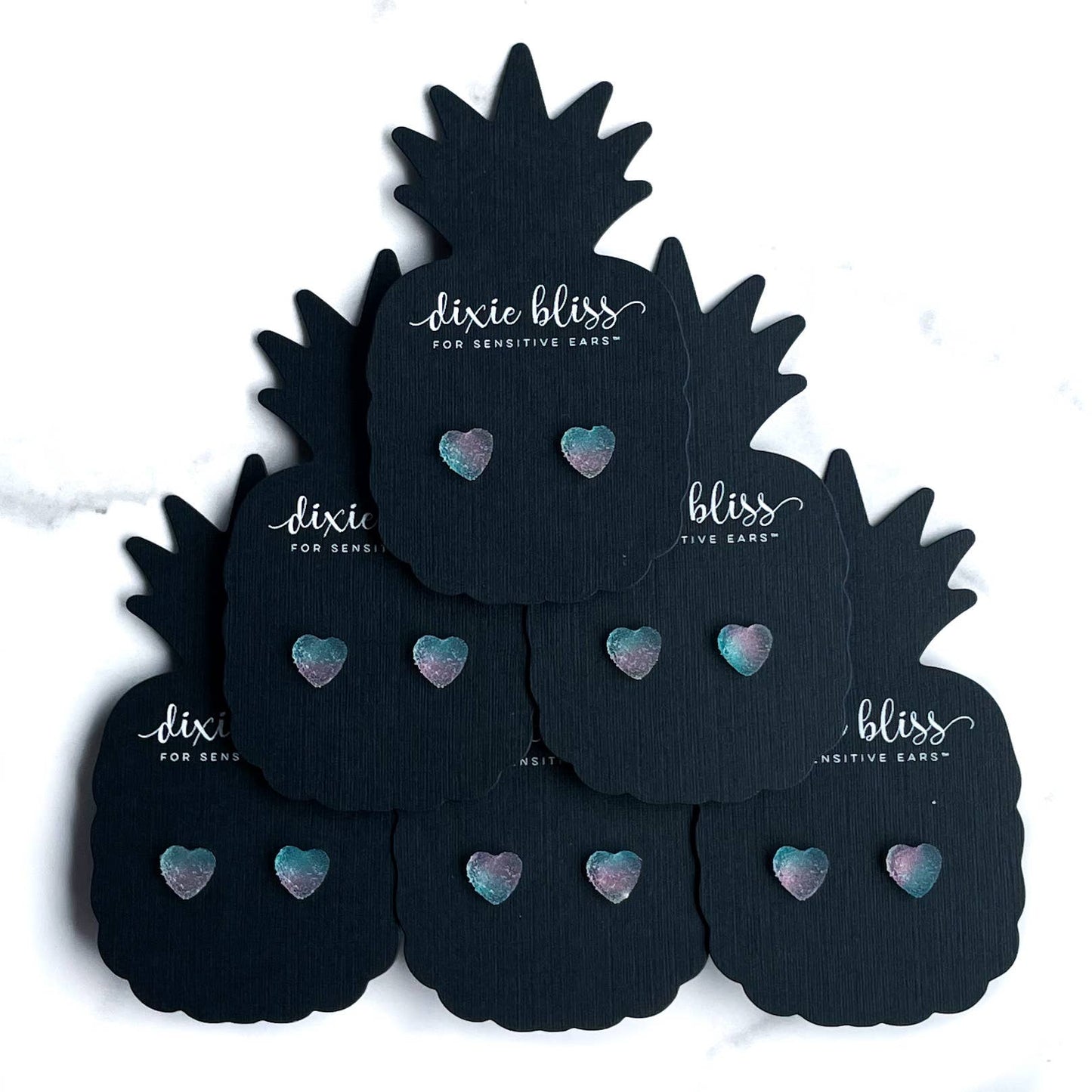 Black pineapple-shaped earplugs with pastel heart designs on display cards.