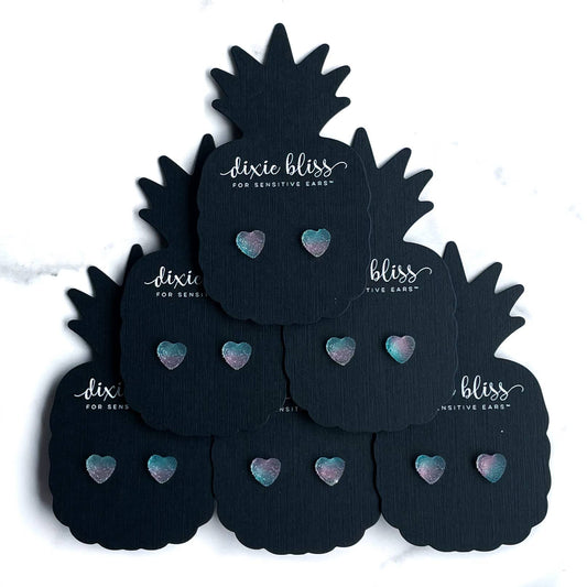 Black pineapple-shaped earplugs with pastel heart designs on display cards.