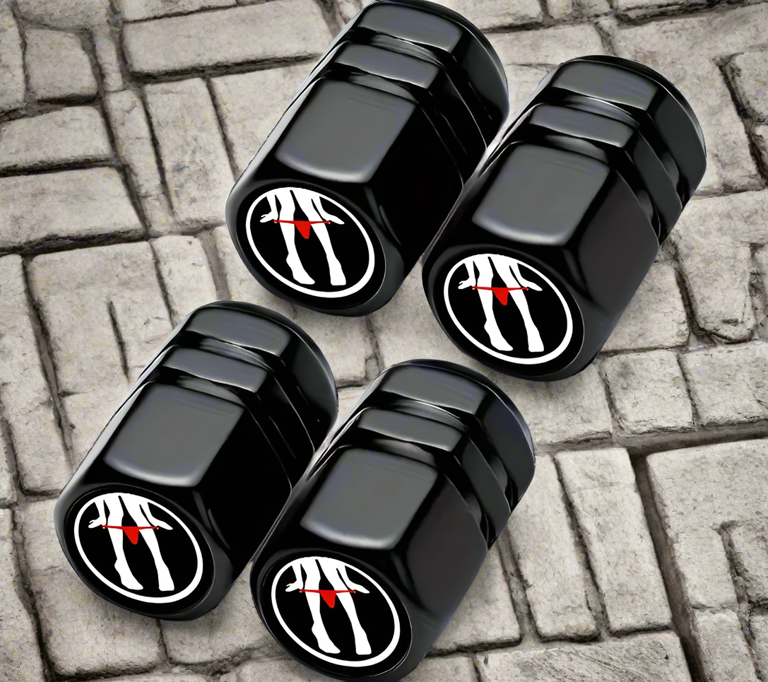 Black tire valve caps with red and white graphic design on a stone surface.