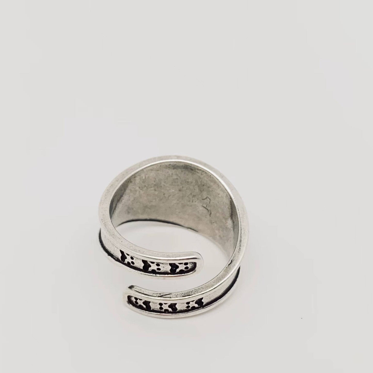 Silver adjustable ring with hammered texture and curved design.