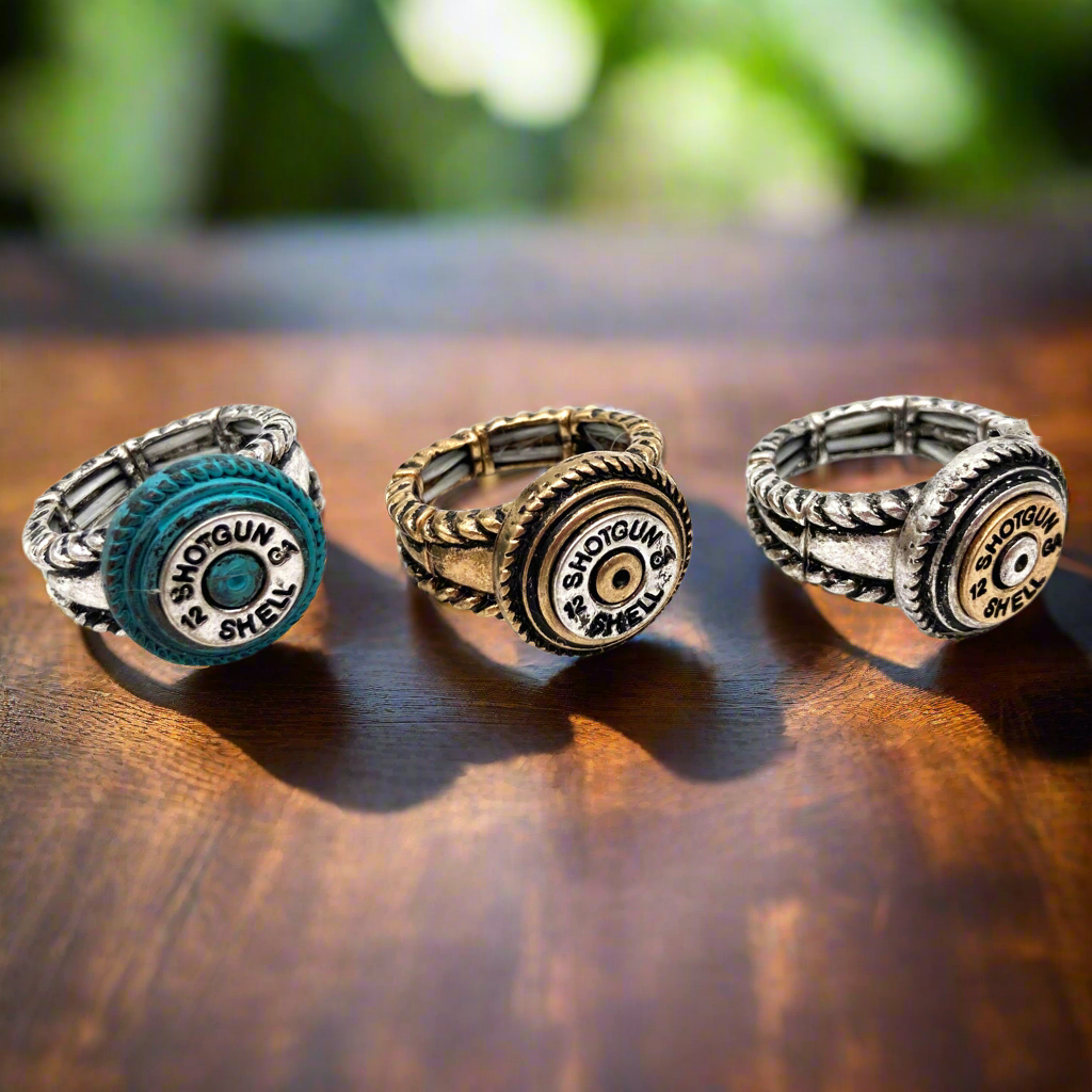 Three shotgun shell-inspired rings on a wooden surface.