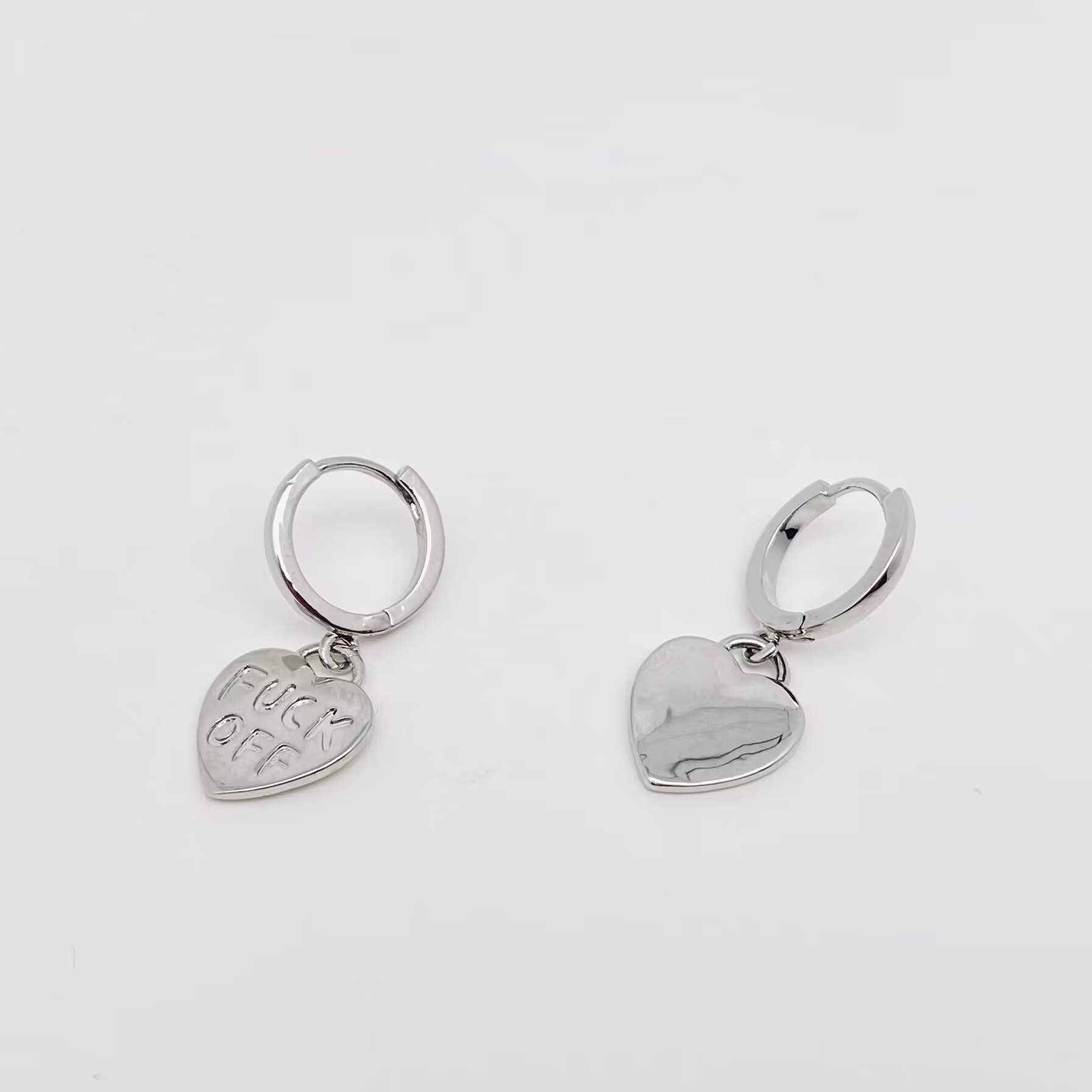 Silver heart-shaped earrings with engraved text and polished finish.