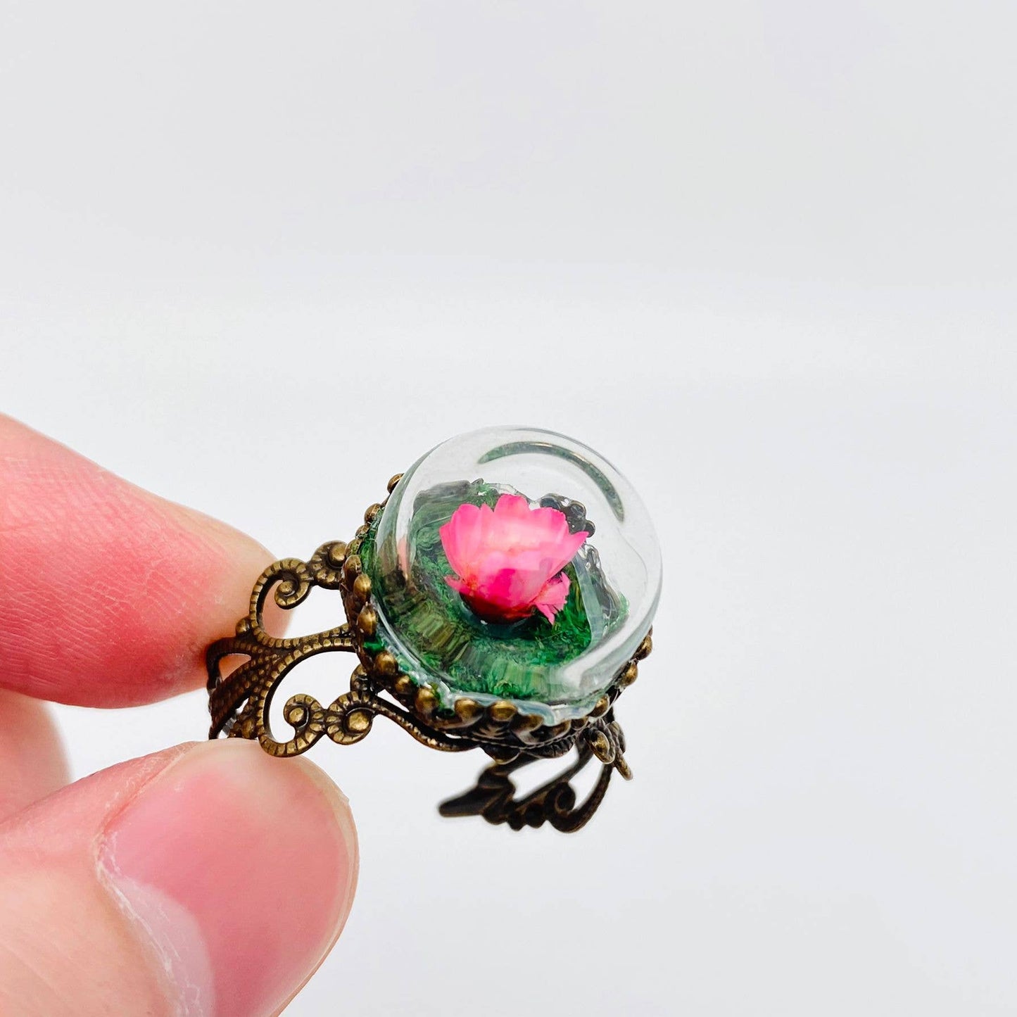 Vintage-style ring with a pink flower in a glass dome.