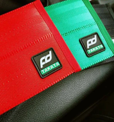 Red and green Takata seatbelt covers with logo.