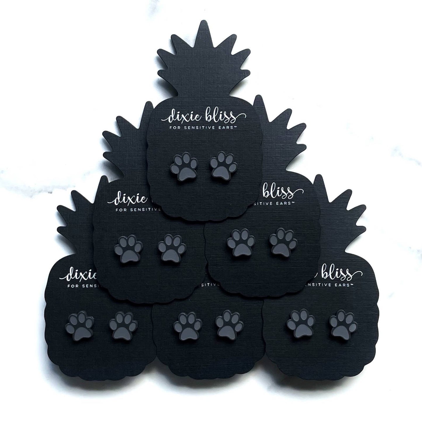 Black Dixie Bliss earplugs with paw prints on display.