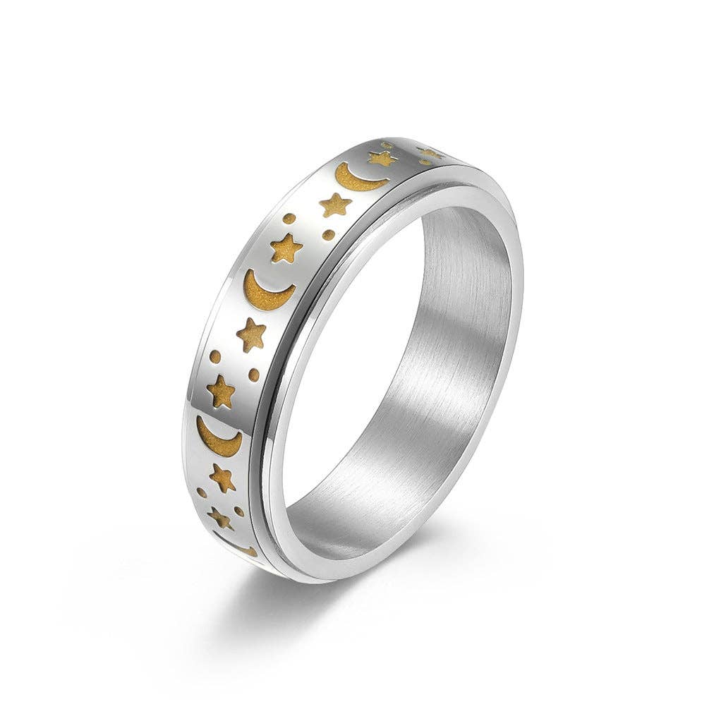 Silver spinner ring with gold moon and star designs.