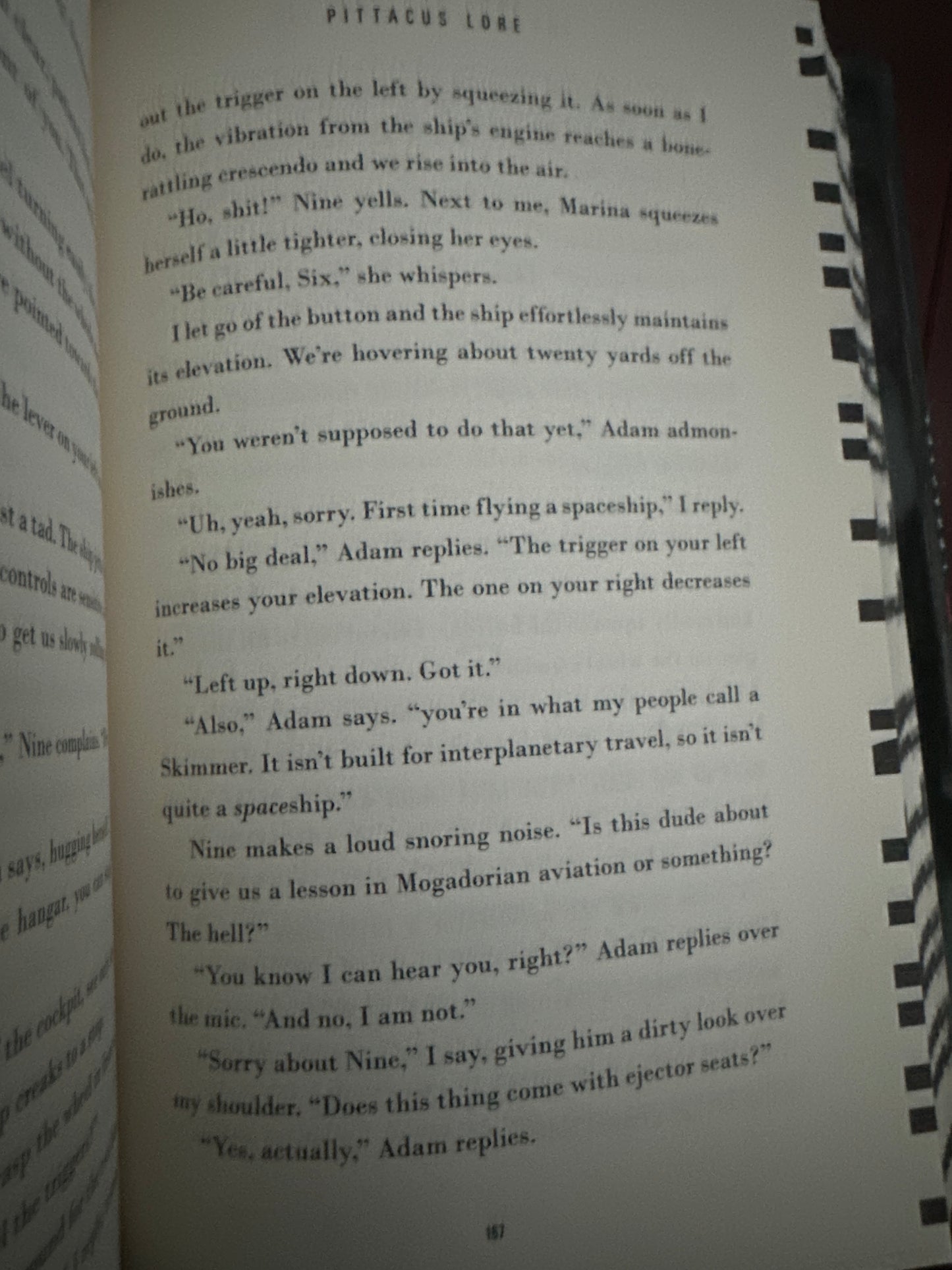 Open book page with text about flying a spaceship in Pittacus Lore series.