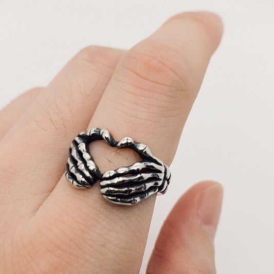 Silver skeleton hand ring on finger, gothic style.