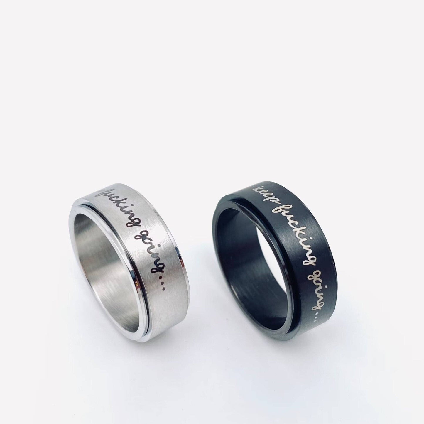 Two spinner rings with keep fucking going... engraved, one silver, one black.