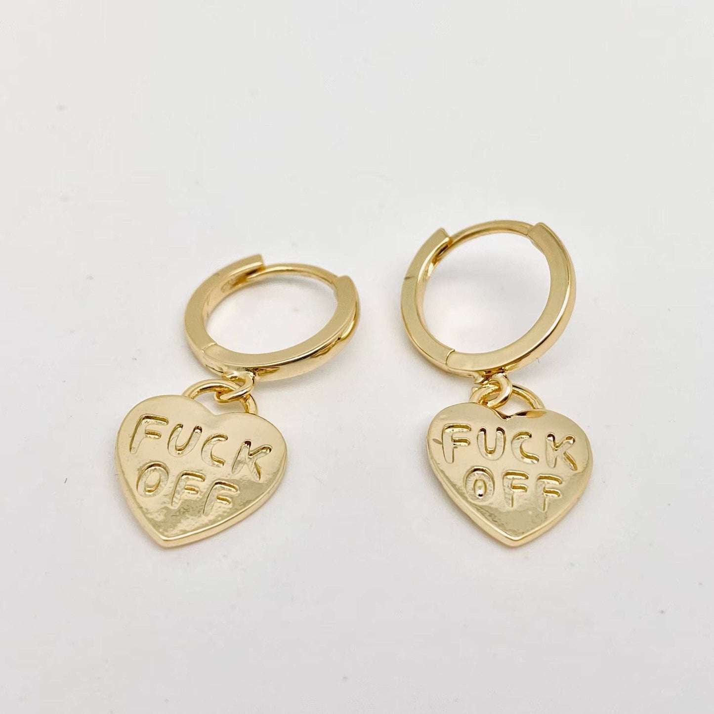 Gold hoop earrings with FUCK OFF engraved heart pendants.