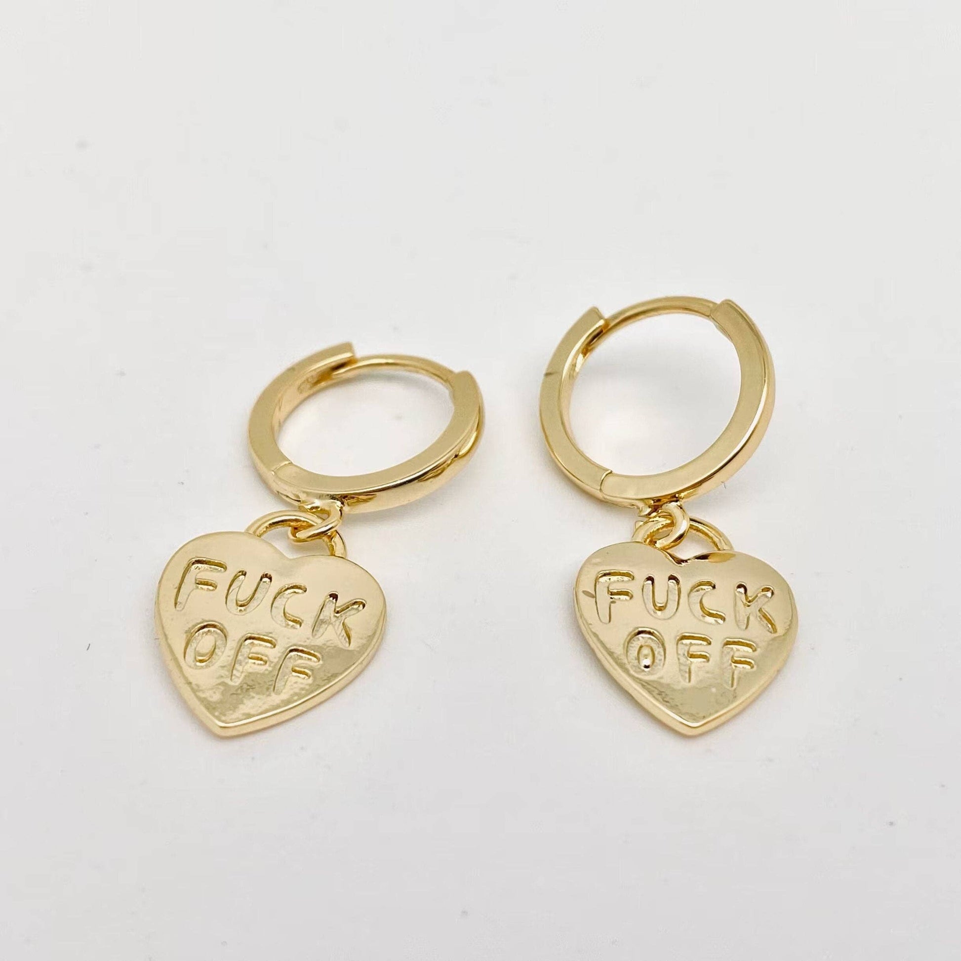 Gold hoop earrings with FUCK OFF engraved heart pendants.