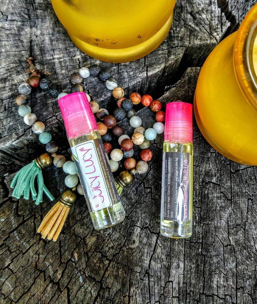 Two pink-lidded essential oil bottles on a wooden surface with beads and jars.