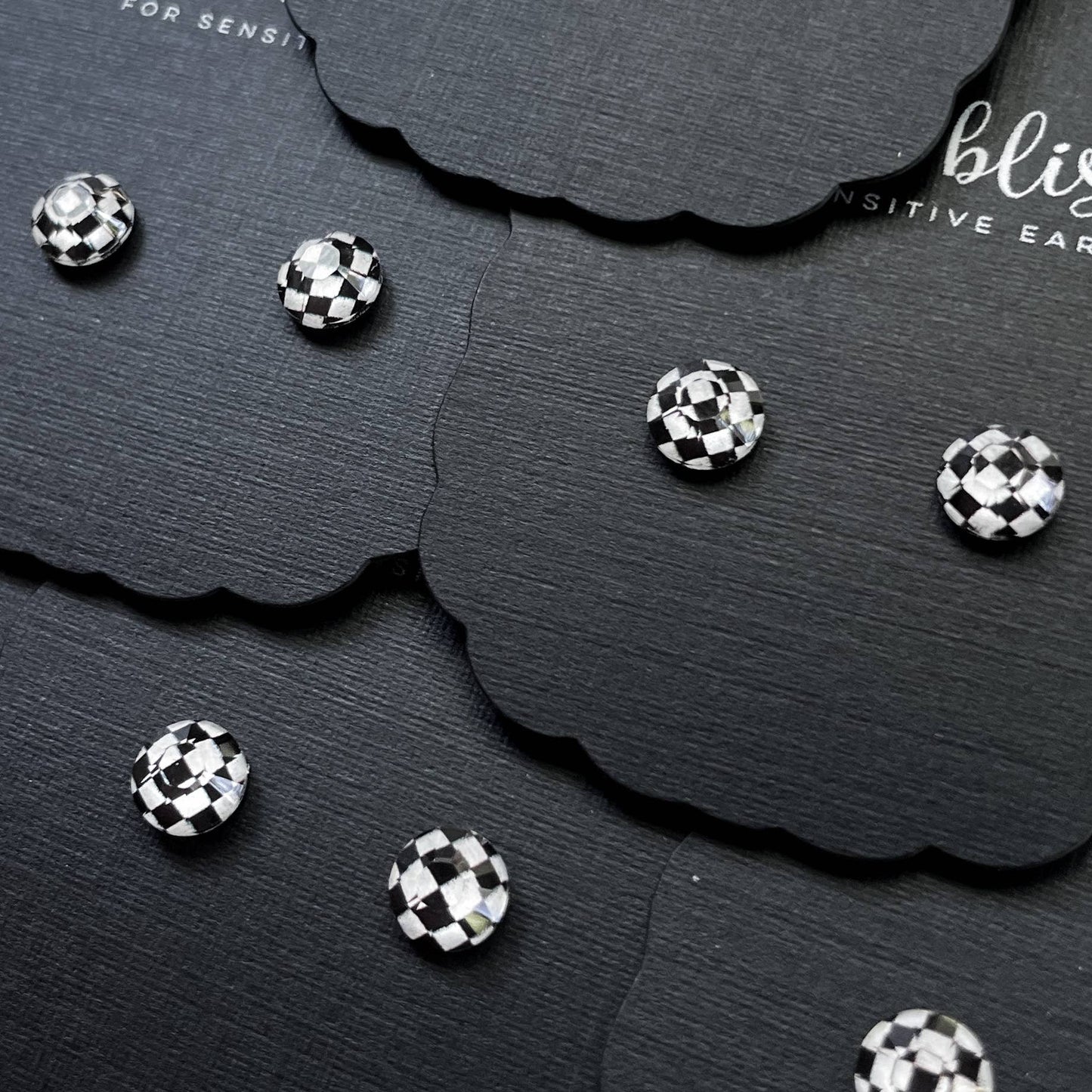 Black and white checkered stud earrings on a black card.