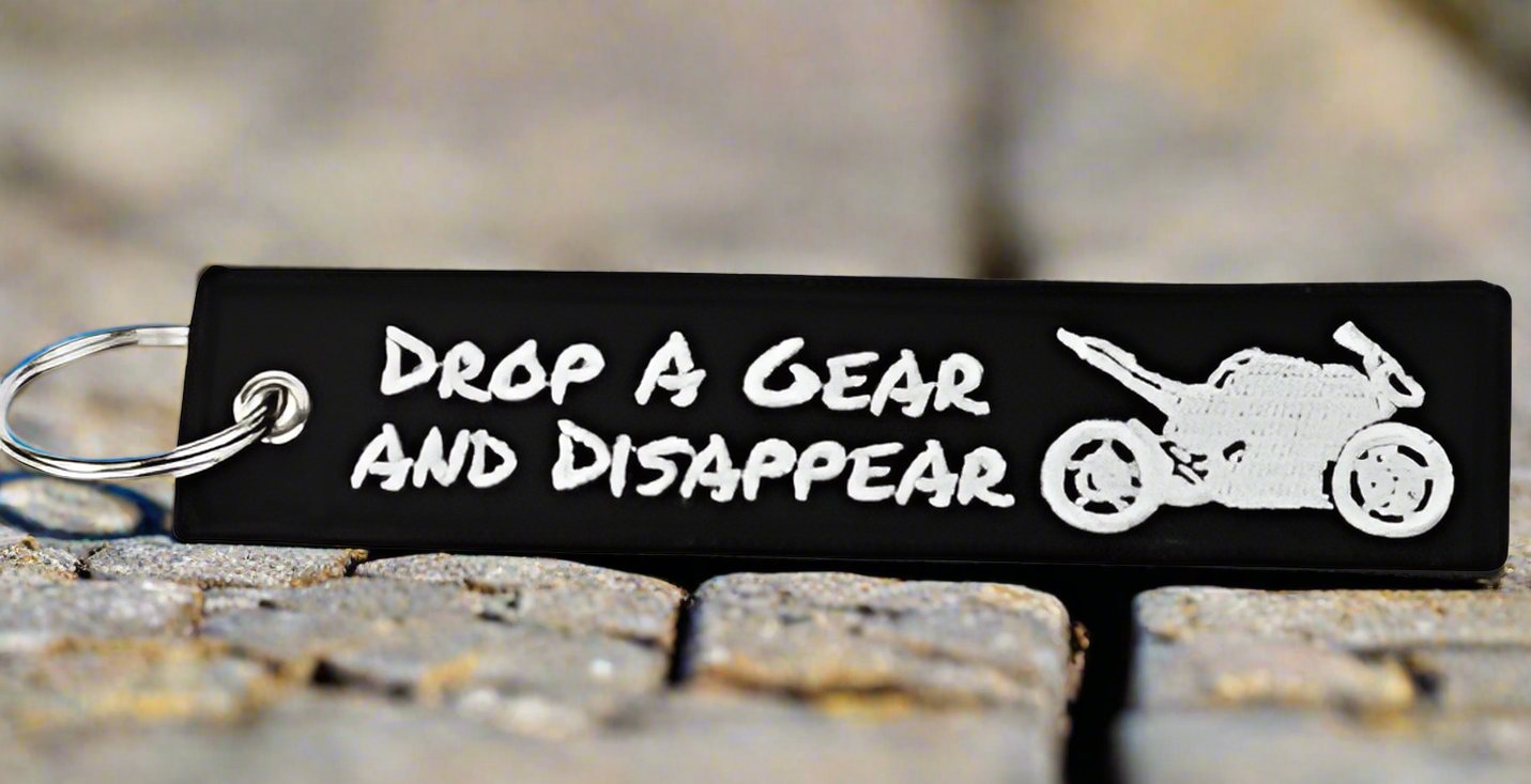 Black keychain with DROP A GEAR AND DISAPPEAR and motorcycle design.