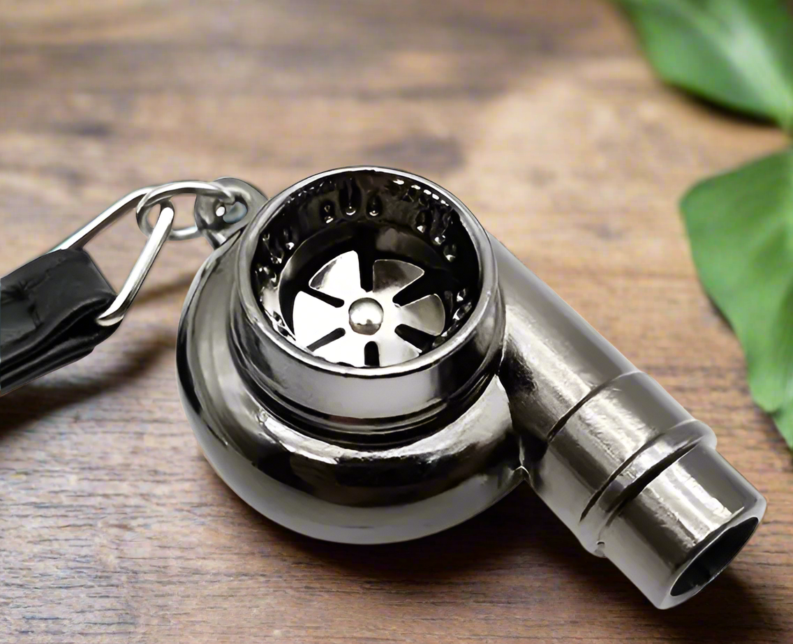 Stainless steel whistle with keychain on wooden surface.