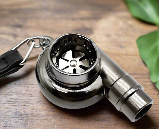 Stainless steel whistle with keychain on wooden surface.