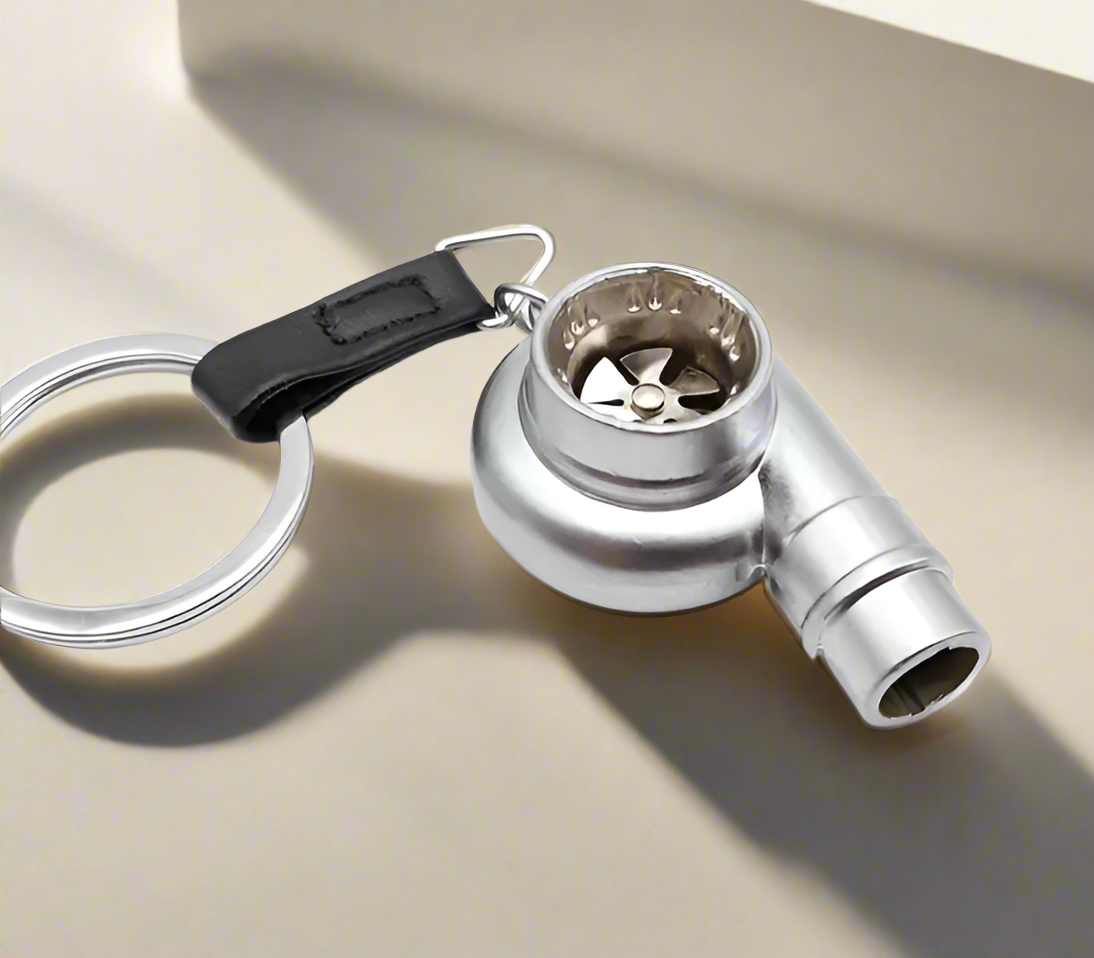 Silver turbo engine keychain with black leather strap and circular ring.