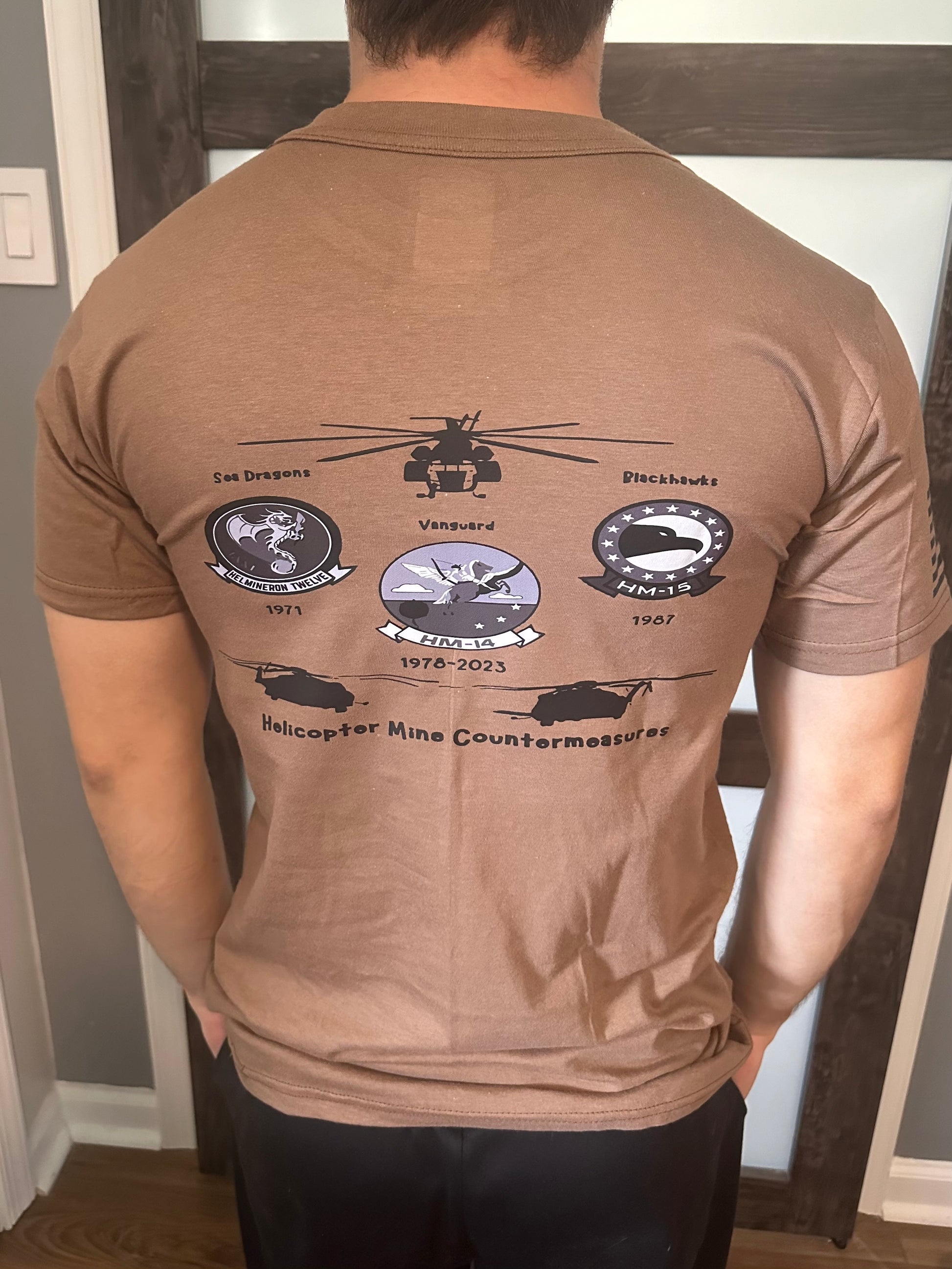 Back of brown t-shirt featuring military helicopter and emblem designs.