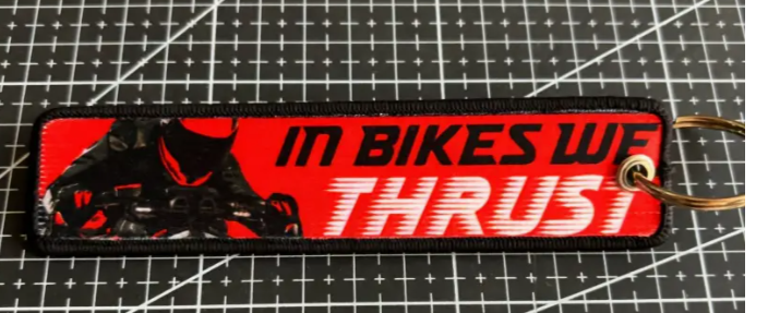 Red keychain with IN BIKES WE THRUST text and motorcycle graphic.