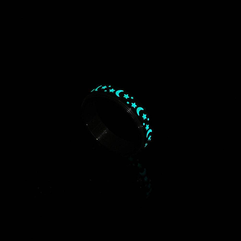Glowing black ring with moon and star designs in the dark.