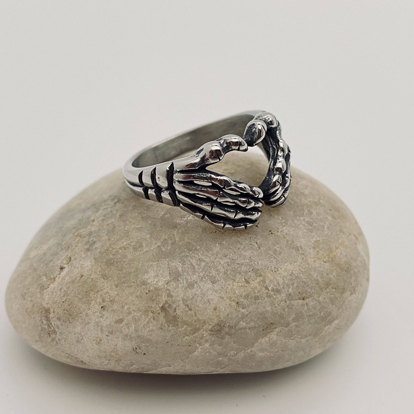 Silver skeleton hand ring on a stone.