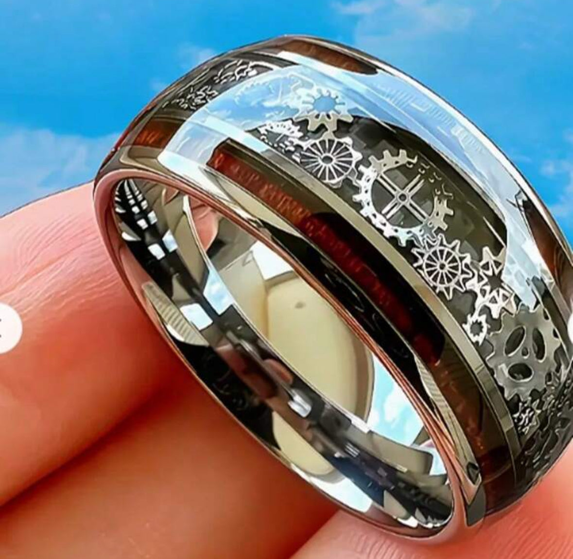 Chrome ring with intricate gear and floral cutouts on a finger.