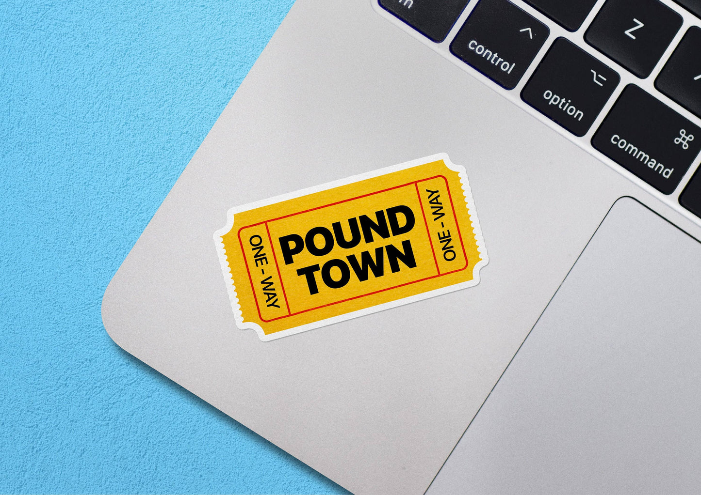 Yellow Pound Town ticket-shaped sticker on laptop keyboard.