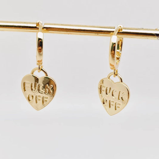 Gold heart-shaped earrings with FUCK OFF engraved on them.
