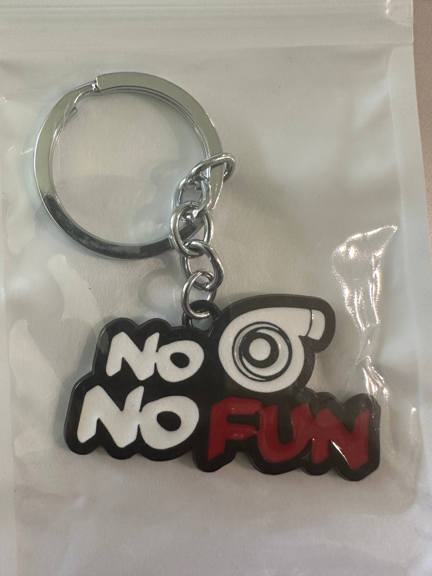Keychain with No No Fun text and eye design in black, white, and red.