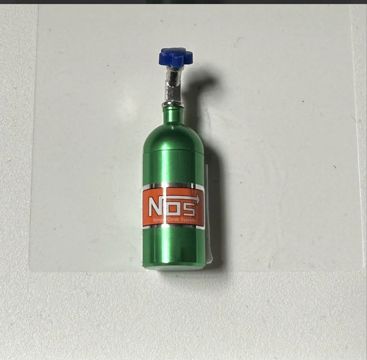 Green NOS nitrous oxide tank with blue nozzle on white background.