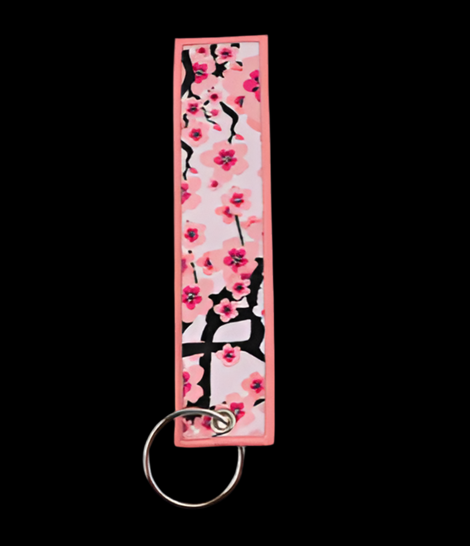 Pink floral keychain with black branches on a white background.