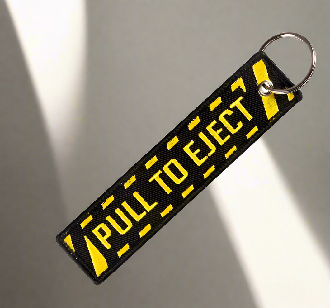 Black keychain with yellow PULL TO EJECT text and ring.