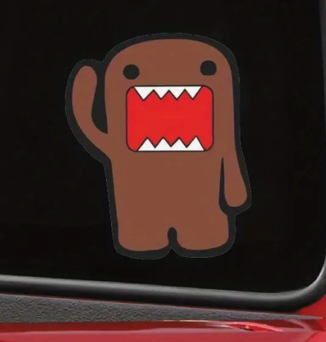Brown Domo sticker with red mouth on black background.