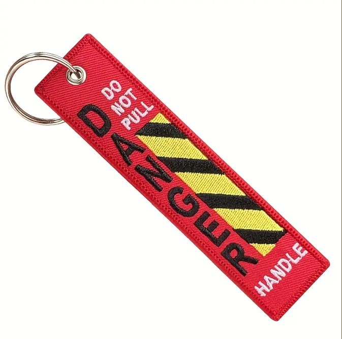 Red keychain with DO NOT PULL DANGER HANDLE text and yellowblack stripes.