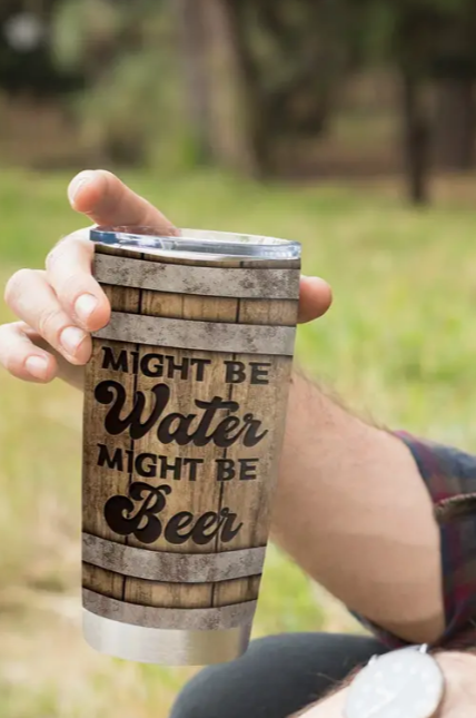 Hand holding rustic tumbler with Might be Water, Might be Beer text.