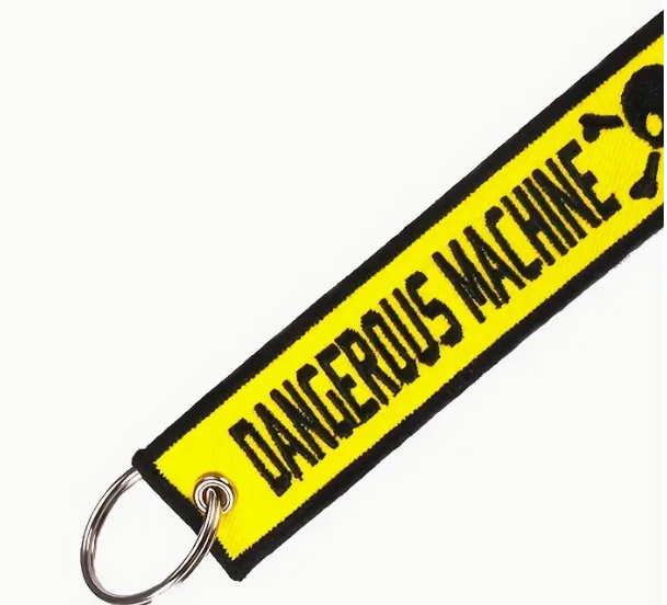 Yellow DANGEROUS MACHINE keychain with black text and metal ring.