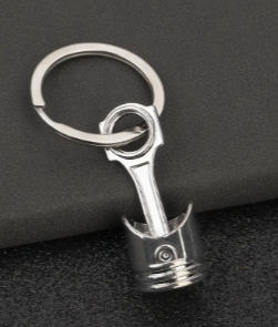Silver piston-shaped keychain with ring and chain.