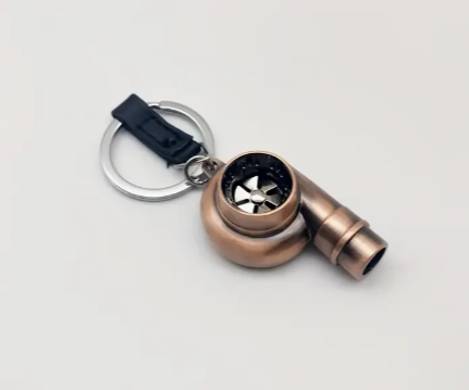 Gold-colored turbo keychain with black ring and silver accents.