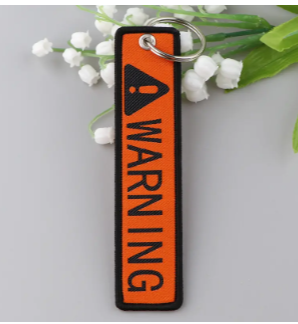 Orange keychain with WARNING text and hazard symbol.