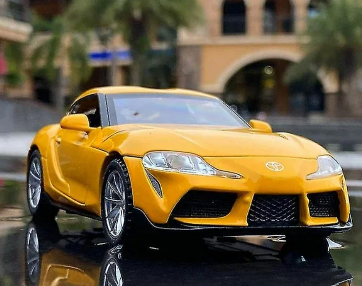 Yellow Toyota sports car model on reflective surface.