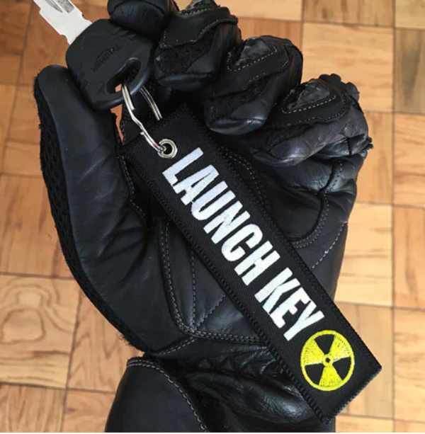 Black leather glove with LAUNCH KEY patch and nuclear symbol.