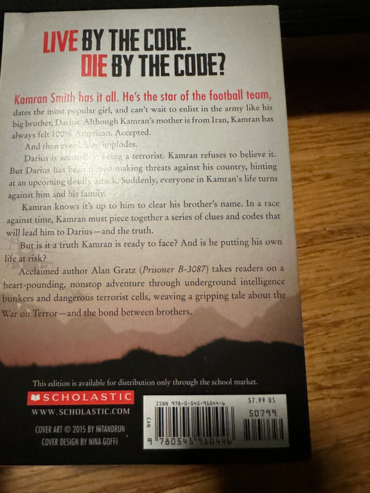 Back cover of a young adult novel titled Live by the Code. Die by the Code by Alan Gratz, featuring a mountain silhouette and Scholastic branding.