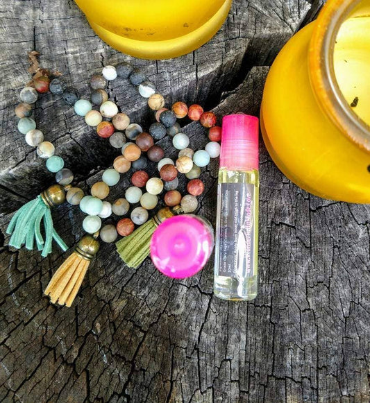 Colorful beaded necklace and essential oil rollerball on rustic wood background.