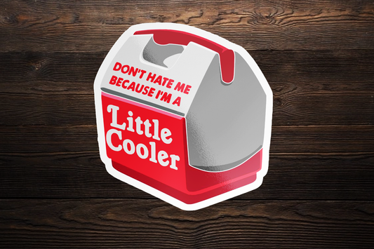 Red and gray sticker shaped like a cooler with text Dont hate me because Im a Little Cooler on wooden background.