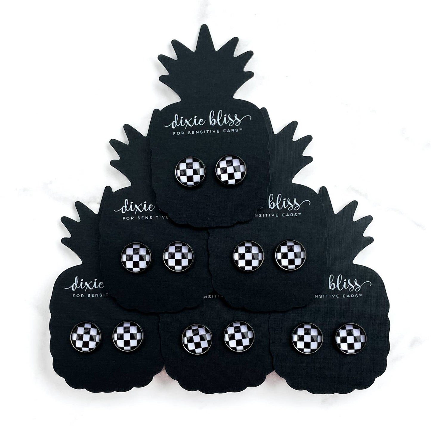 Black pineapple-shaped display with checkered earplugs by Dixie Bliss.
