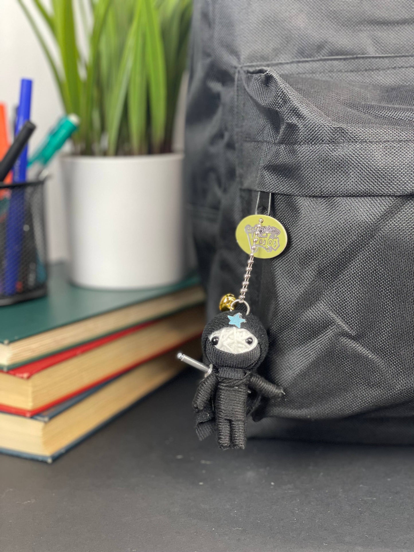 Black ninja plush charm with bell, attached to backpack.
