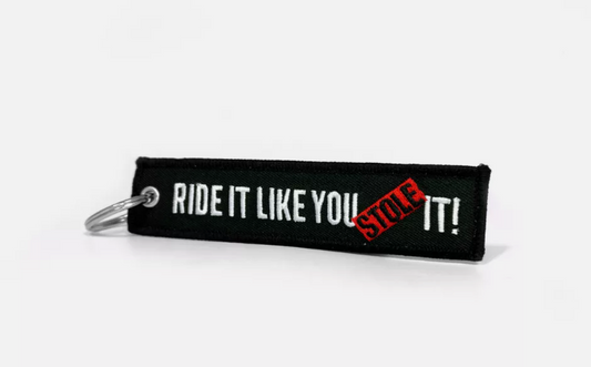 Black keychain with RIDE IT LIKE YOU STOLE IT text in white and red.