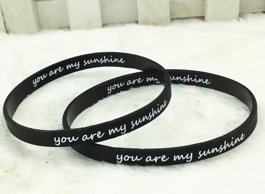 Black you are my sunshine wristbands on white surface.