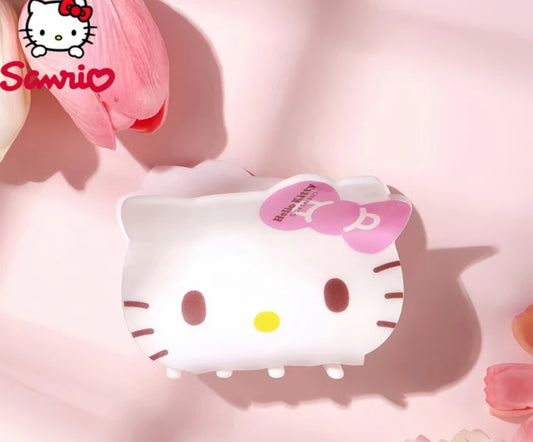 Hello Kitty-themed white hair clip with pink bow on a soft pink background.